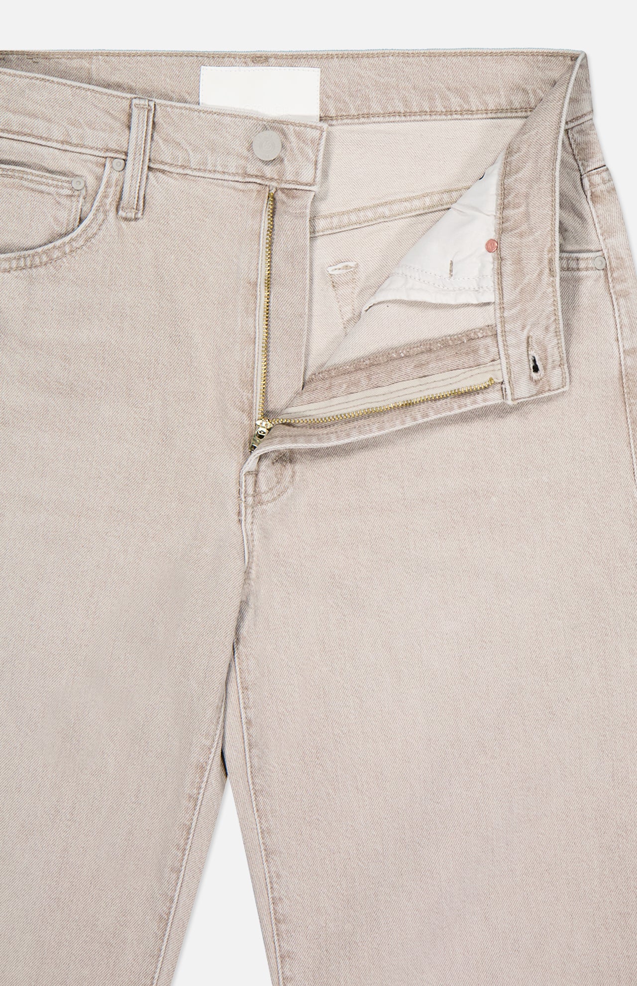 A close-up of The Dodger Slouchy Fit Sneak Pants by MOTHER, in light beige denim with a straight leg, open waistband and fly revealing a gold zipper and white pocket lining, laid flat on a white background.