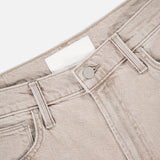 Close-up of the waistband and top of The Dodger Slouchy Fit Sneak Pants by MOTHER in light beige, highlighting the front button, belt loops, and part of the pocket against a white background.