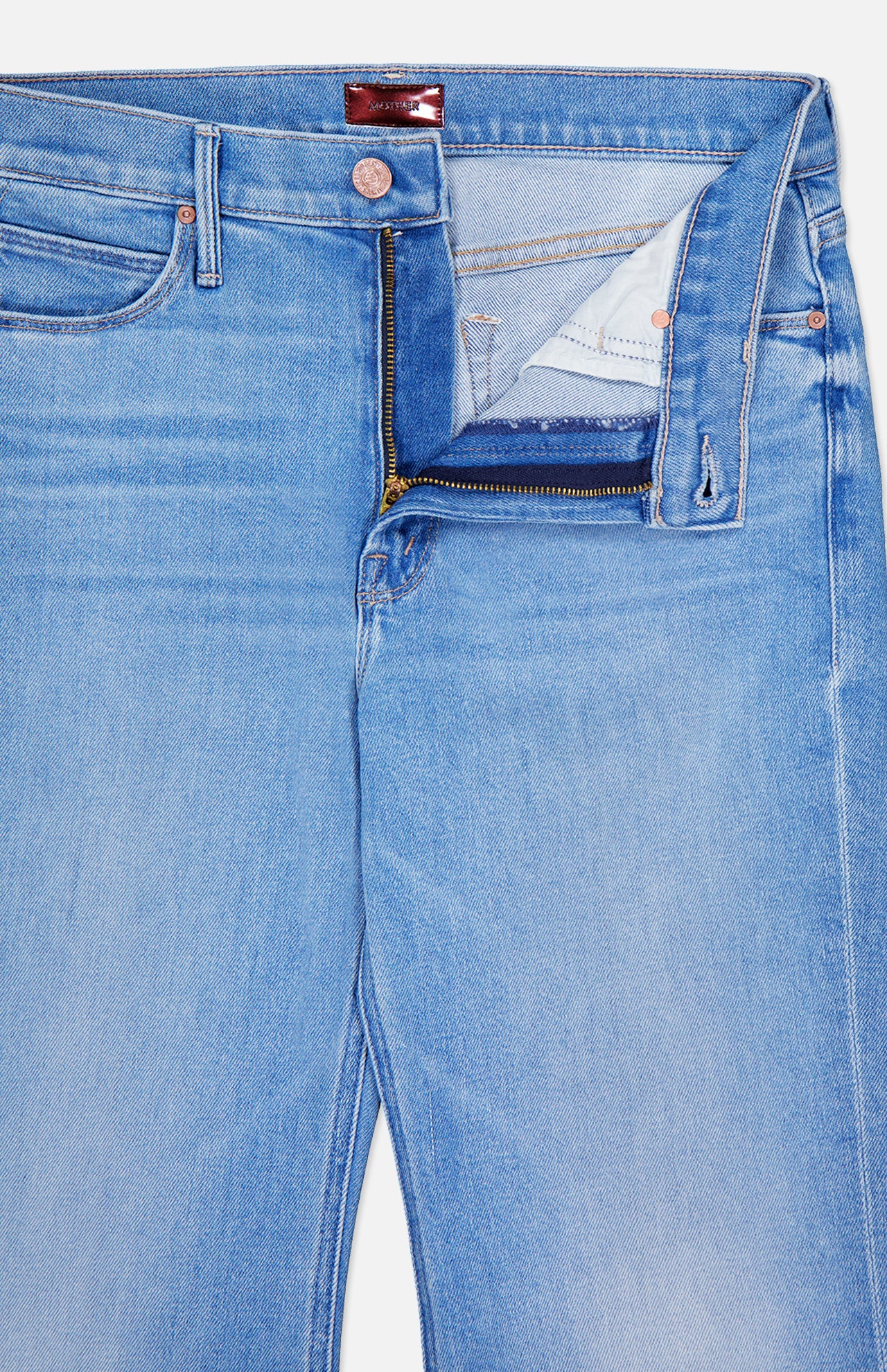 The Doozy Jean in Room Service by MOTHER features light blue denim with a subtle vintage-inspired fade. Shown with the top button undone and zipper partially open, revealing the inside waistband and pocket lining.