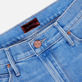 Close-up of The Doozy Jean in Room Service by MOTHER, highlighting the blue denim waistband, copper button, belt loops, front pockets, and a brown leather brand patch on the inner waistband.