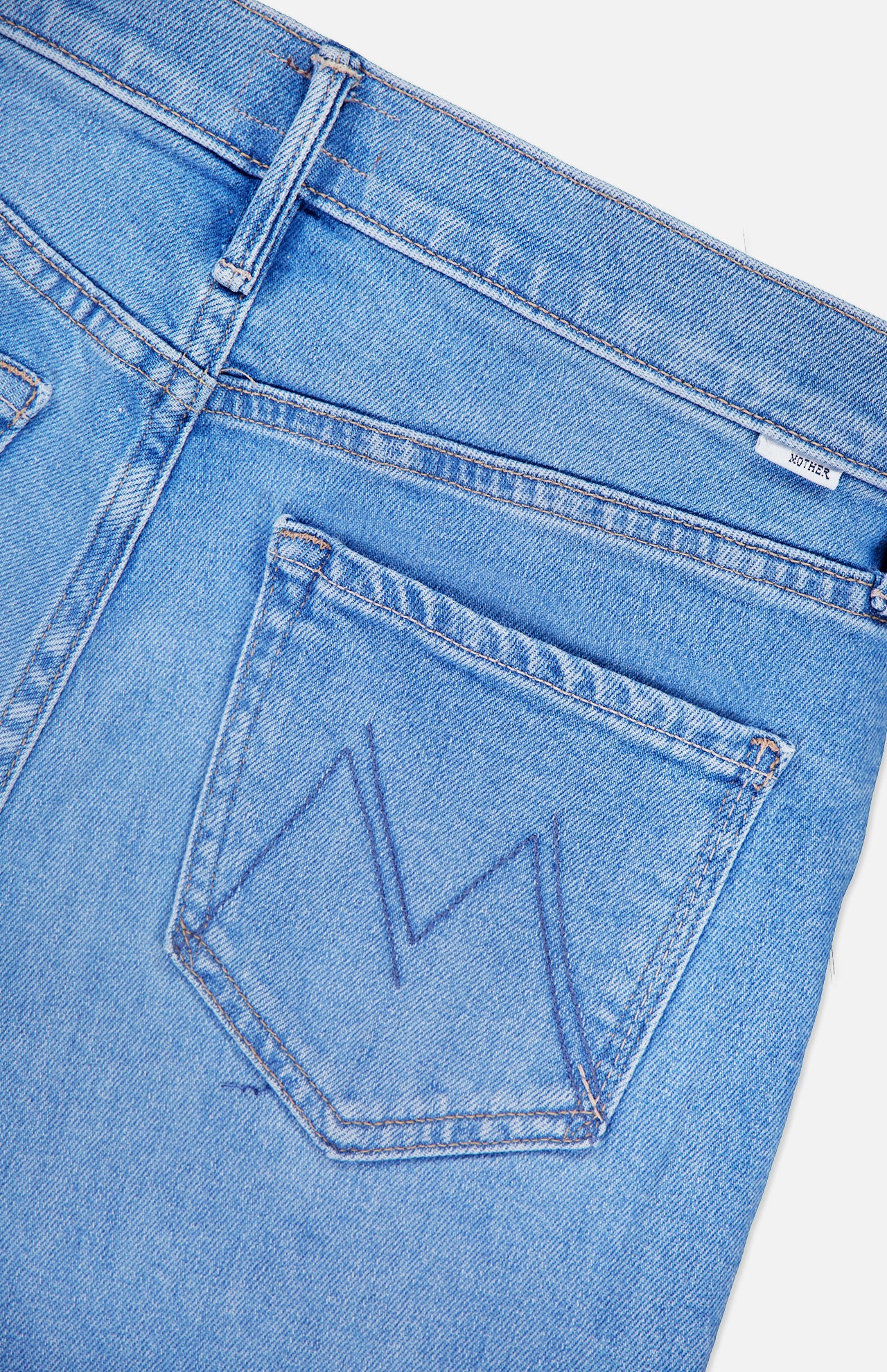 Close-up of the back of MOTHER's The Doozy Jean in Room Service, showcasing a stitched M on the back pocket and a visible waistband belt loop.