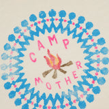 The Flirt Squad Tank Top by MOTHER is an off-white crew neck featuring a campfire illustration and colorful CAMP MOTHER design, accented with a blue and pink circular pattern for a vintage-inspired look.