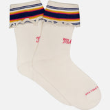 The Fold Please Socks by MOTHER are cream ankle-length embroidered socks with ruffled tops featuring blue, yellow, and red stripes. Pink text on the sides and soles reads "Mother" and "Loves You.