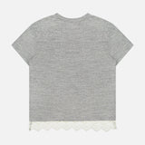 The Footballer Lace T-shirt by MOTHER is an oversized gray cotton tee with short sleeves and a round neckline, shown from the back. It features a scalloped white lace trim along the bottom hem for a unique twist on sporty style.