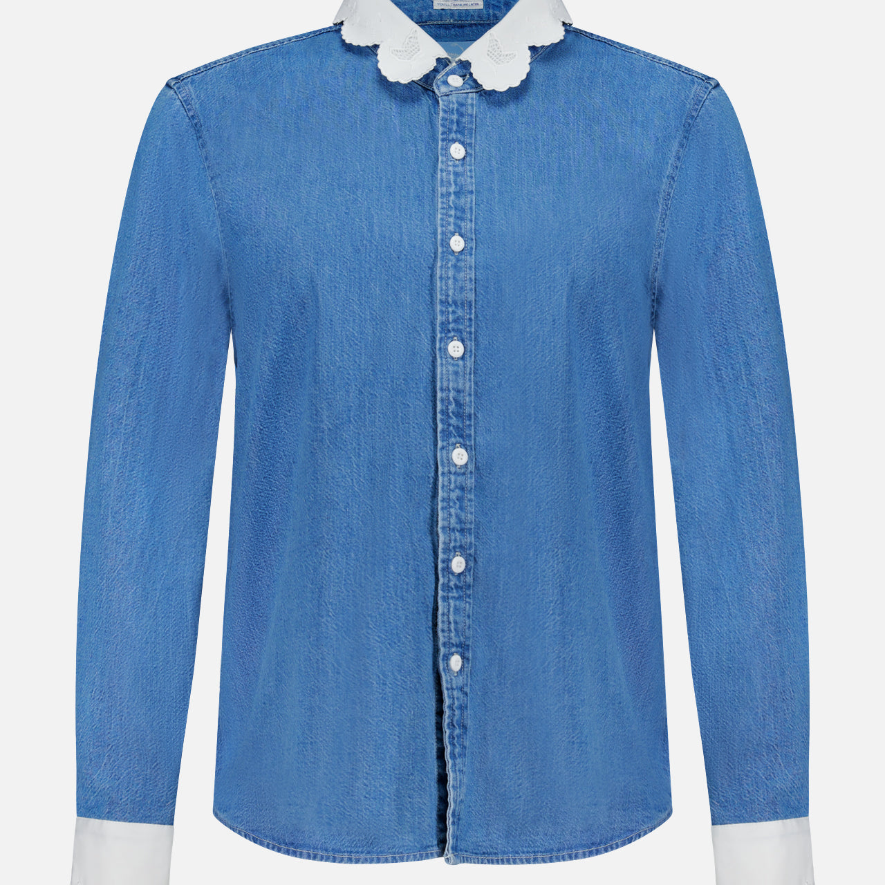 The Frilly Foxy Boxy Denim Shirt by MOTHER is a 100% cotton button-down with long sleeves, white scalloped trim on the collar and cuffs, and detailed white embroidered accents for a chic touch.