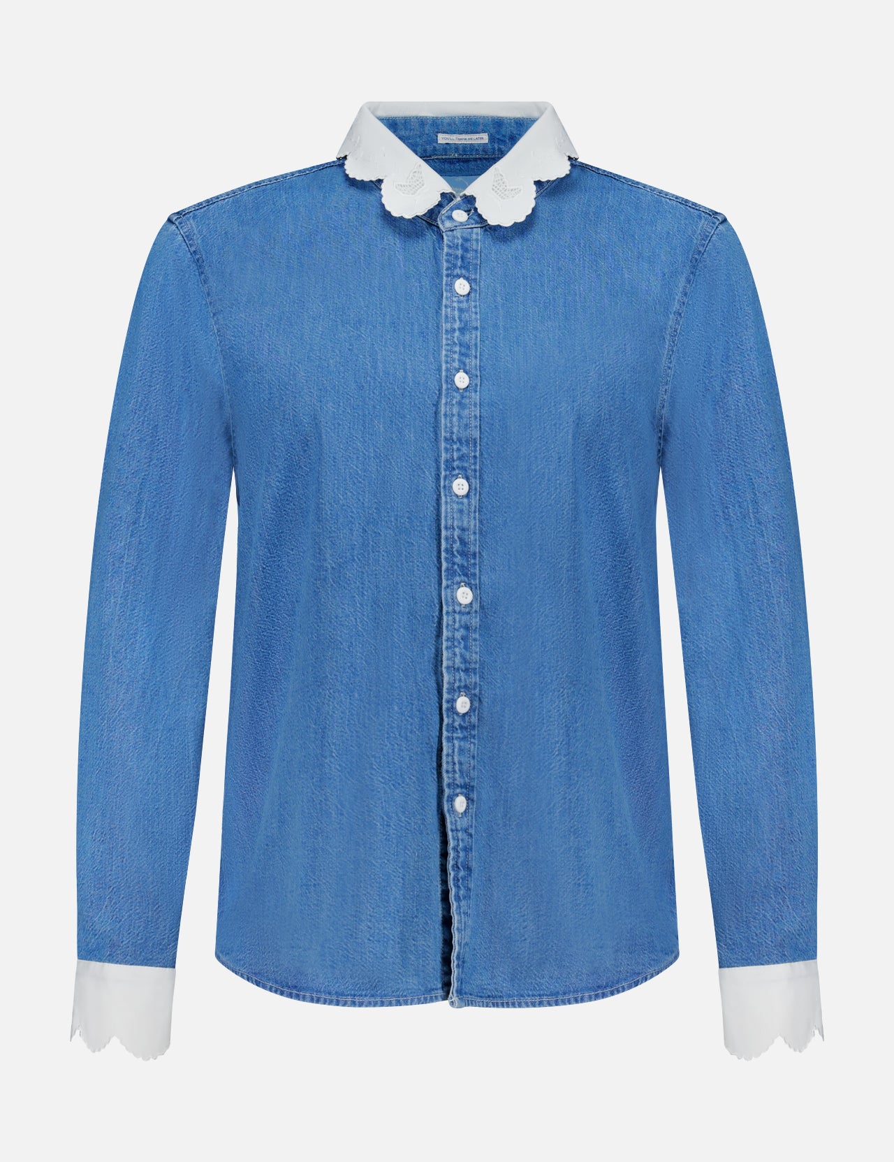 The Frilly Foxy Boxy Denim Shirt by MOTHER is a 100% cotton button-down with long sleeves, white scalloped trim on the collar and cuffs, and detailed white embroidered accents for a chic touch.