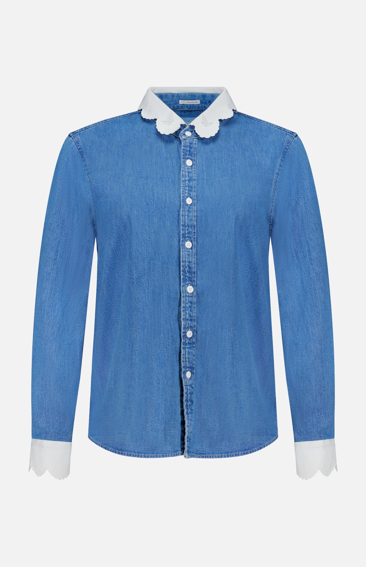 The Frilly Foxy Boxy Denim Shirt by MOTHER is a 100% cotton button-down with long sleeves, white scalloped trim on the collar and cuffs, and detailed white embroidered accents for a chic touch.