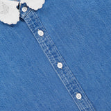 Close-up of The Frilly Foxy Boxy Denim Shirt by MOTHER: a blue 100% cotton button-down with white buttons and a scalloped, butterfly-embroidered collar featuring delicate white trim.