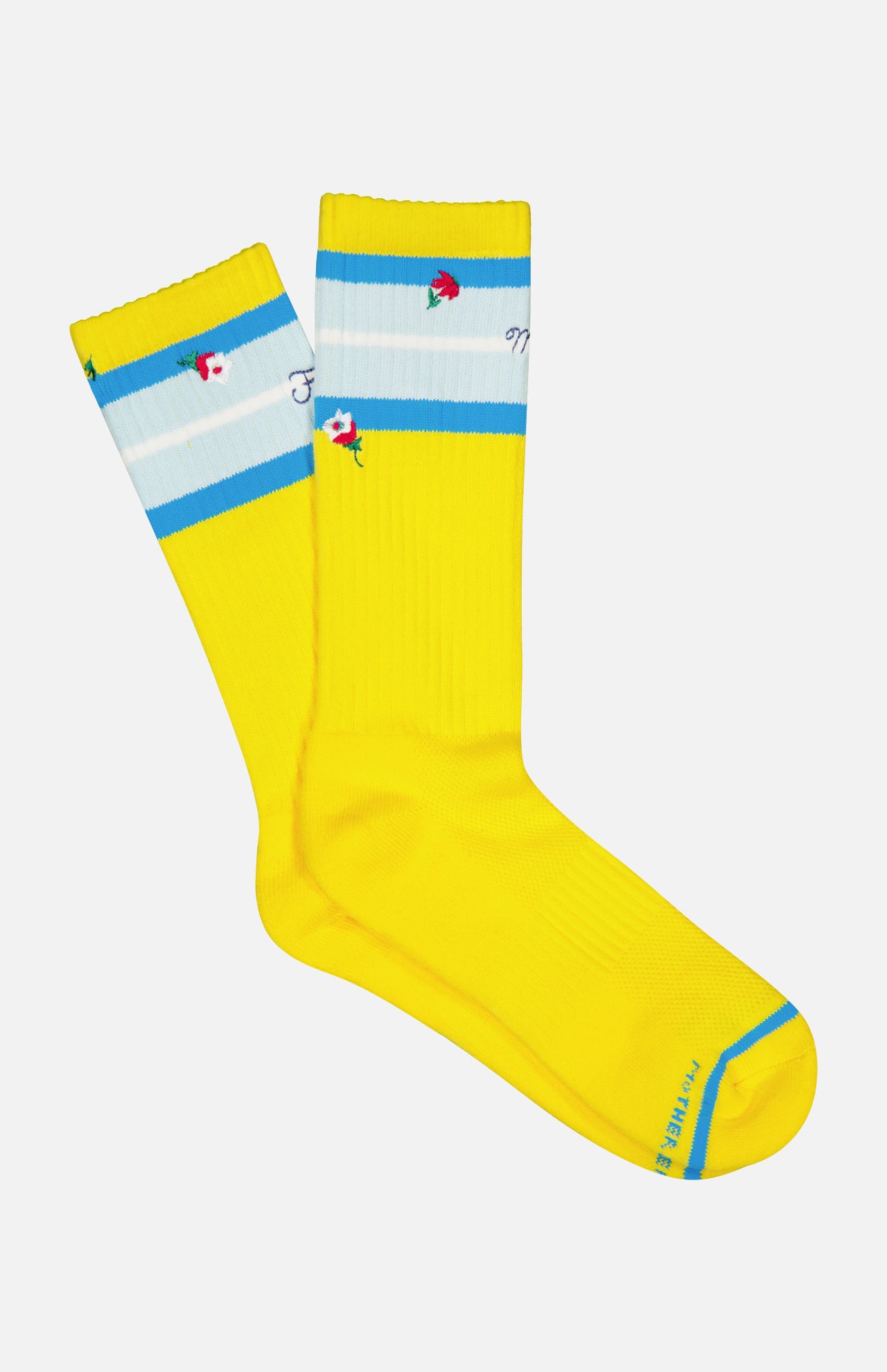 The Half-Calf Socks by MOTHER are bright yellow organic cotton tube socks with a ribbed texture, light blue and white stripes at the top, red and green embroidered roses, and blue text on the toe.