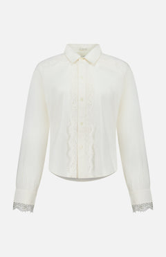 The Headup Honey Shirt by MOTHER is a white long-sleeve blouse with lace trim along the button placket and cuffs, featuring a classic collar and button-down front that combines timeless elegance with subtle western-inspired detailing, displayed on a plain white background.