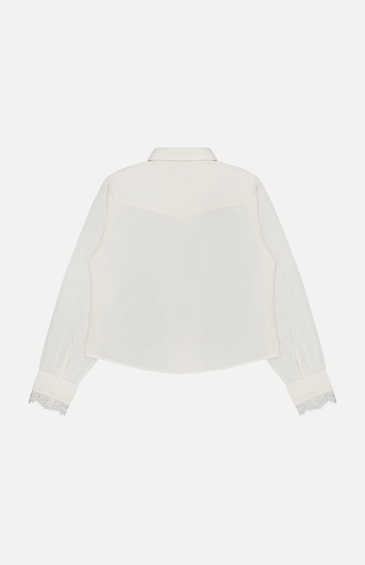 The Headup Honey Shirt by MOTHER is a white long-sleeve blouse, featuring lace trim on the cuffs and shown from the back against a plain white background. Designed with a collar and a slightly curved hem, it offers a subtle western-inspired silhouette.