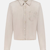 The Honor Roll Cropped Shirt by MOTHER is a light beige women's button-up with long sleeves, a pointed collar, single chest pocket, and cropped hem, shown on a plain white background.