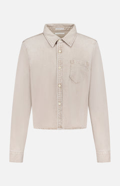 The Honor Roll Cropped Shirt by MOTHER is a light beige women's button-up with long sleeves, a pointed collar, single chest pocket, and cropped hem, shown on a plain white background.