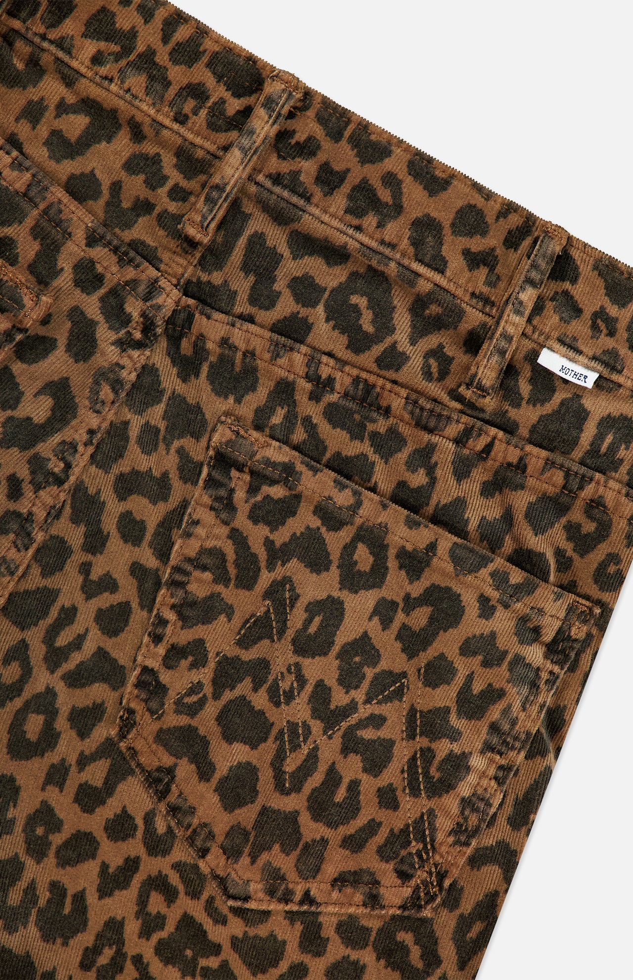Close-up of The Hustler Flood Pant in Leap Year by MOTHER, featuring brown stretch corduroy with a black leopard print, front pocket, belt loops, and a small white label near the waistband.