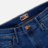 Close-up of the waistband and pockets of The Insider Skimp Jean in Taking Chances by MOTHER, showcasing blue stretch denim, a copper button, belt loops, and a brown interior label for classic vintage style.
