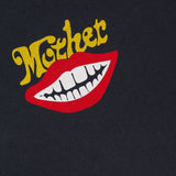 A graphic of red lips with white teeth is printed below the word MOTHER in yellow, stylized text on a dark fabric background. The Itty Bitty Ringer T-shirt by MOTHER features a shrunken crew neck, cropped hem, and is crafted from recycled cotton, blending bold design with sustainable style.