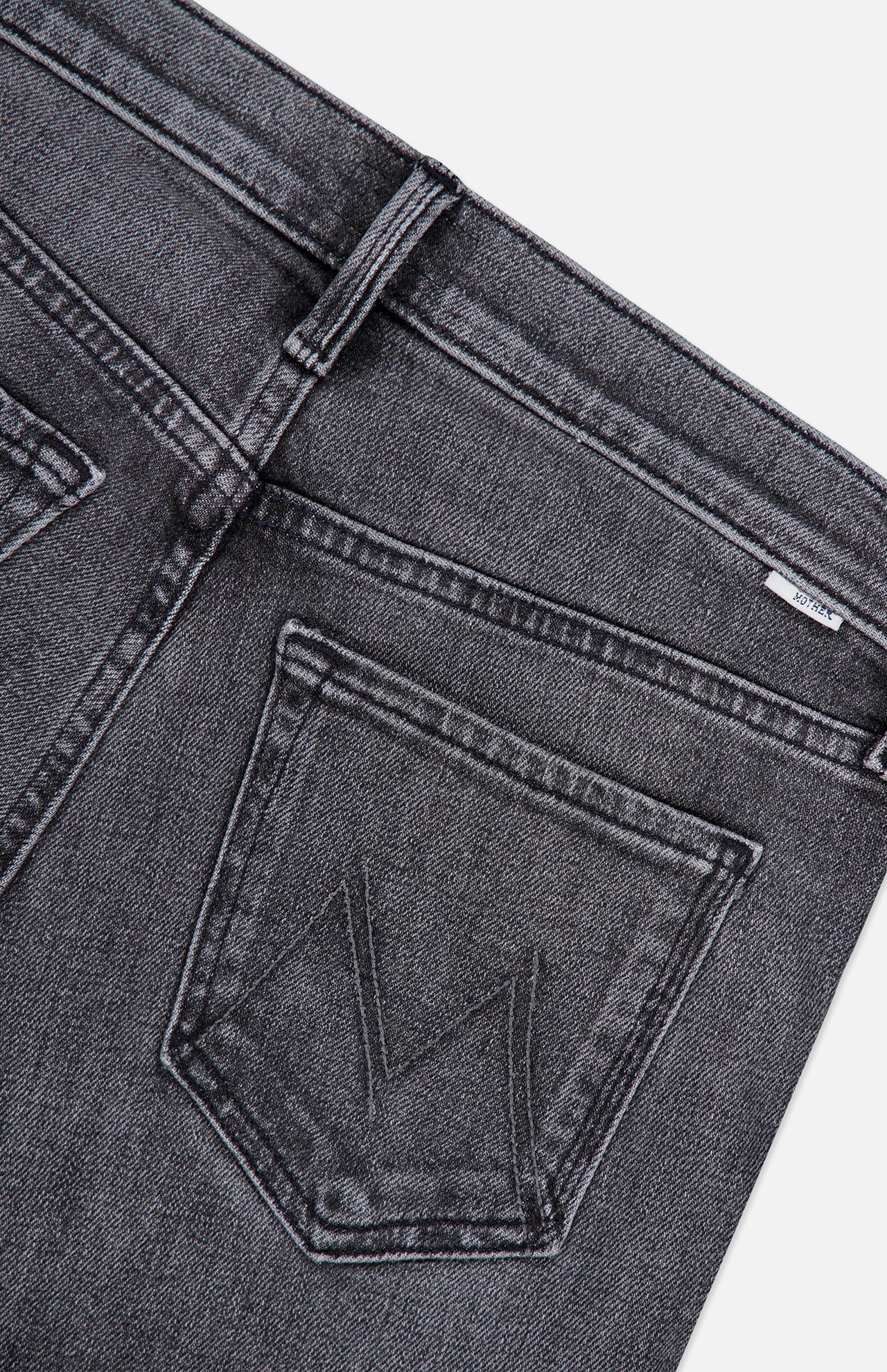 Close-up of the back of The Jinx Sneak Jeans in Cliffhanger by MOTHER, crafted from dark grey stretch denim, featuring two back pockets with stitching detail and a small white tag near the waistband, shot against a white background.