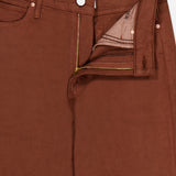 A close-up of The Kick It Pant in Bison by MOTHER showcases the high-rise silhouette, with a visible zipper and button fly partially unzipped to reveal pocket lining and waistband details. The straight-leg cut is subtly highlighted, emphasizing the pant’s classic style elements.