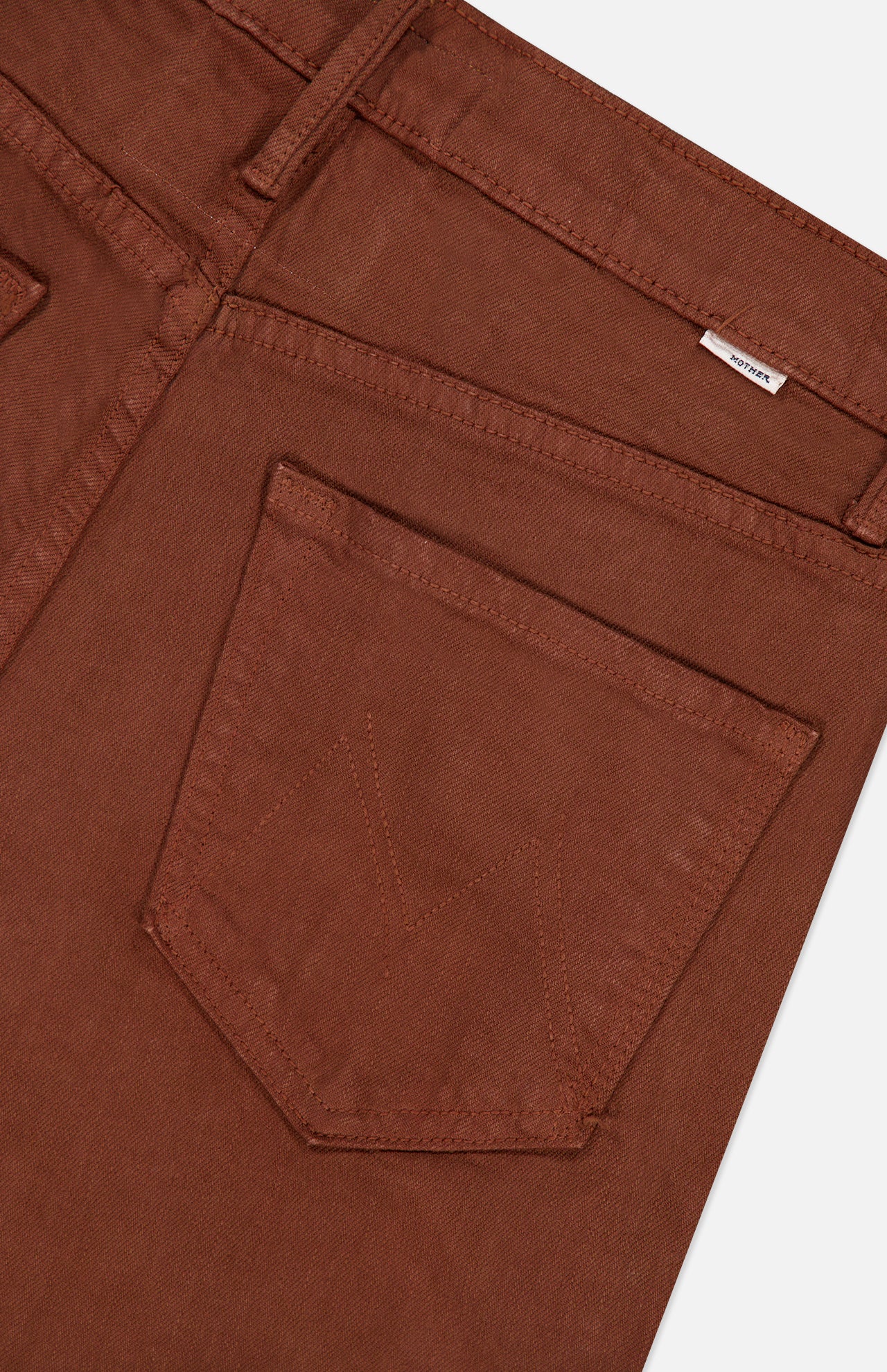 Close-up of the back pocket area of MOTHER’s The Kick It Pant in Bison, featuring visible stitching and a small white label near the waistband.