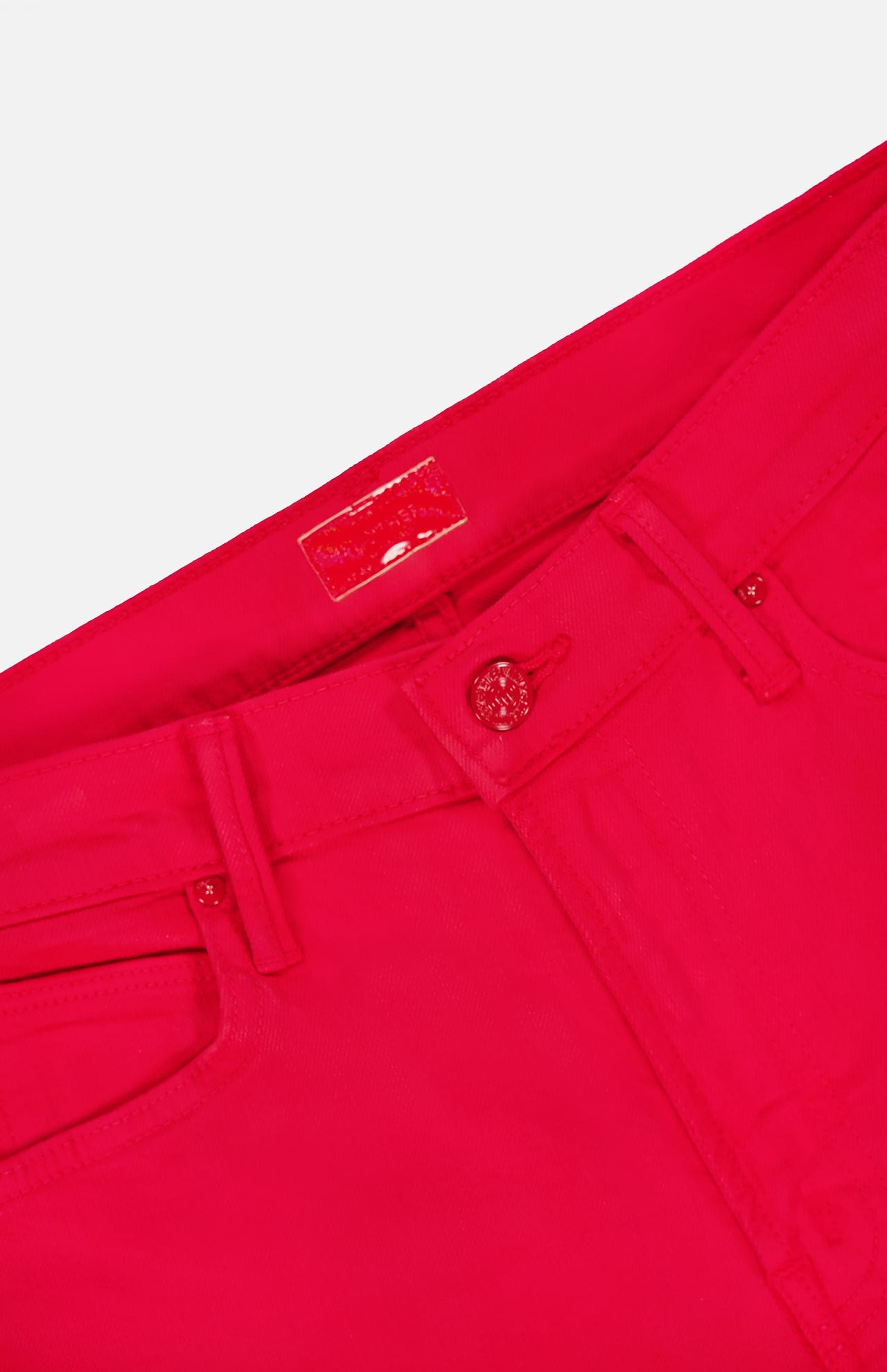 Close-up of the waistband and upper section of The Kick It Pant in Tango Red by MOTHER, featuring a button closure, belt loops, pockets, and a rectangular label on the inner waistband.