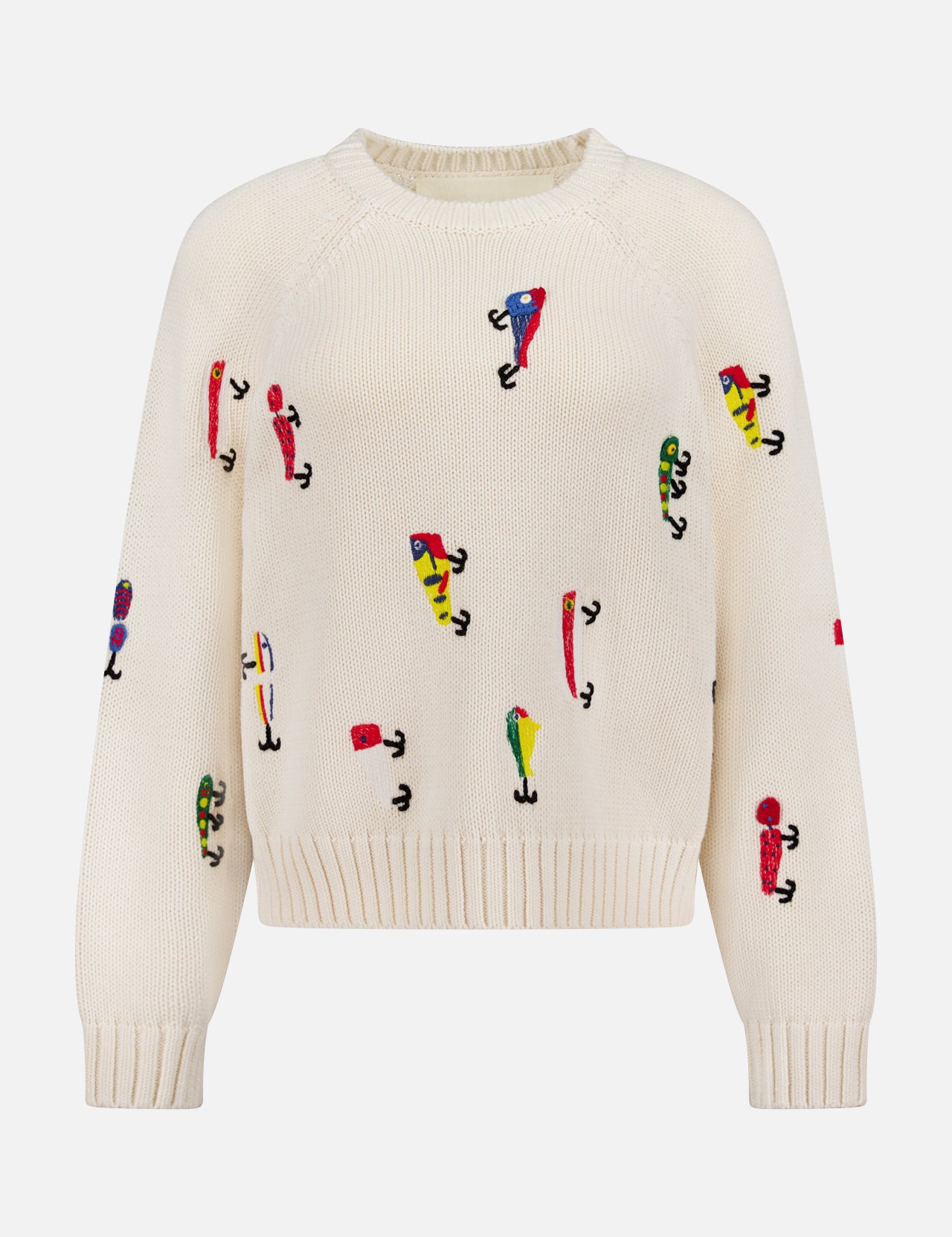 The Raglan Pullover Sweater by MOTHER is a cream-colored 100% cotton sweater with colorful abstract embroidered figures in various poses across the front, sleeves, and body.