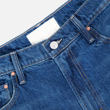 Close-up of the waistband and upper front of MOTHER The Rerun Zip Sneak Floral Print Jeans, featuring a metal button, front pockets, orange stitching, and a blank white label inside.