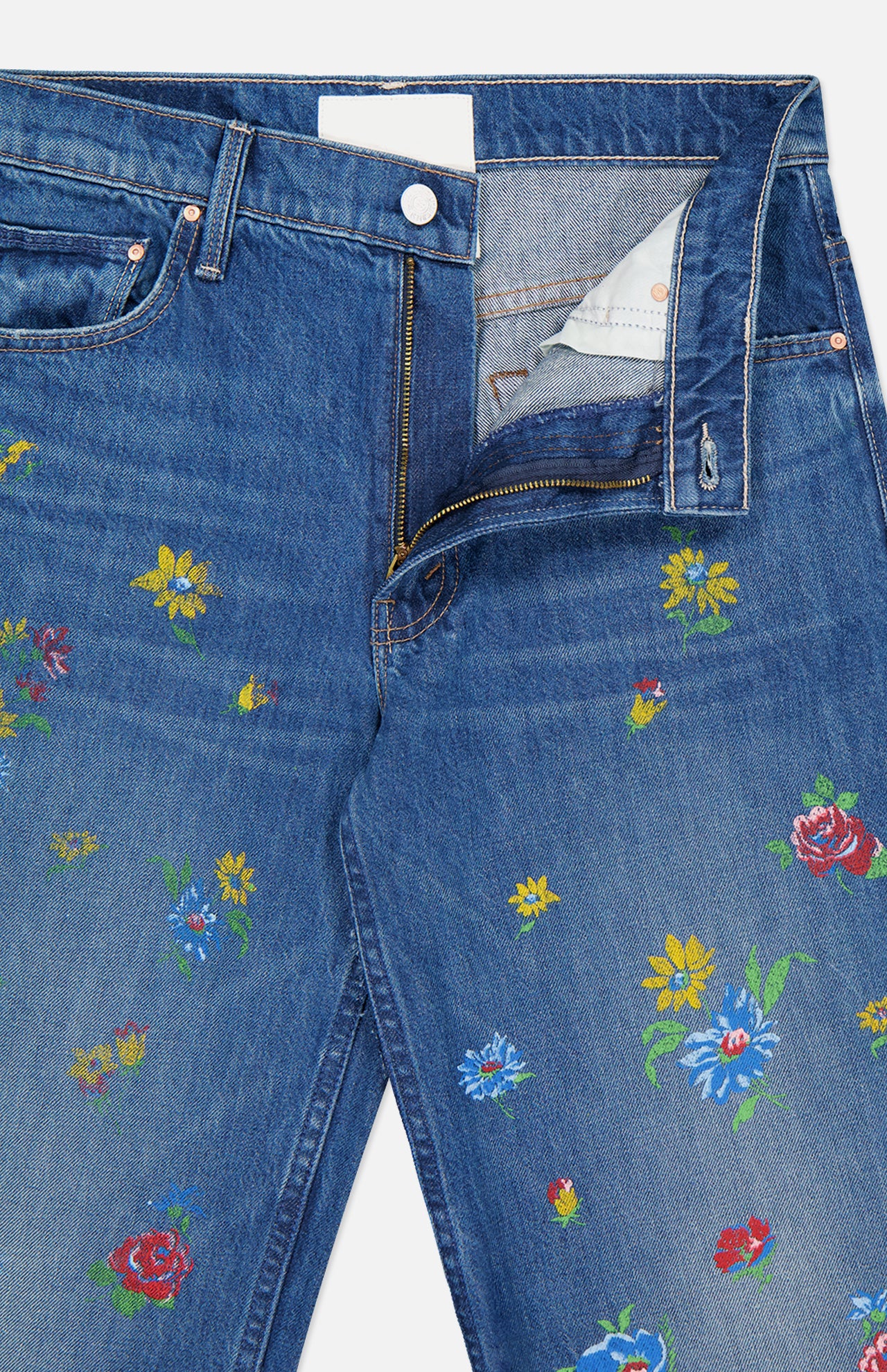 The Rerun Zip Sneak Floral Print Jeans by MOTHER feature blue denim, a high waist, partially open zipper and button, and painterly red, yellow, and blue embroidered flowers scattered across the fabric.