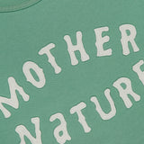 Close-up of The Short Sleeve Concert Shirt by MOTHER, a green 100% cotton raglan sweatshirt featuring raised white "MOTHER NATURE" lettering in a playful, wavy arc across the fabric.