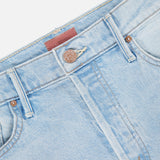Close-up of the waistband and upper front of The Vagabond Mini Fray Skirt by MOTHER in light blue denim, featuring a metal button, belt loops, pockets, tan stitching, and subtle frayed hem details.