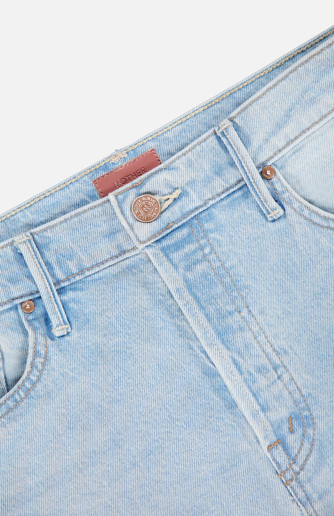 Close-up of the waistband and upper front of The Vagabond Mini Fray Skirt by MOTHER in light blue denim, featuring a metal button, belt loops, pockets, tan stitching, and subtle frayed hem details.