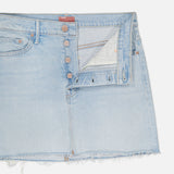 The Vagabond Mini Fray Skirt by MOTHER features a light blue, low-slung fit with a raw frayed hem, classic five-pocket styling, and a partially open button fly revealing white pocket lining. Shown against a white background.
