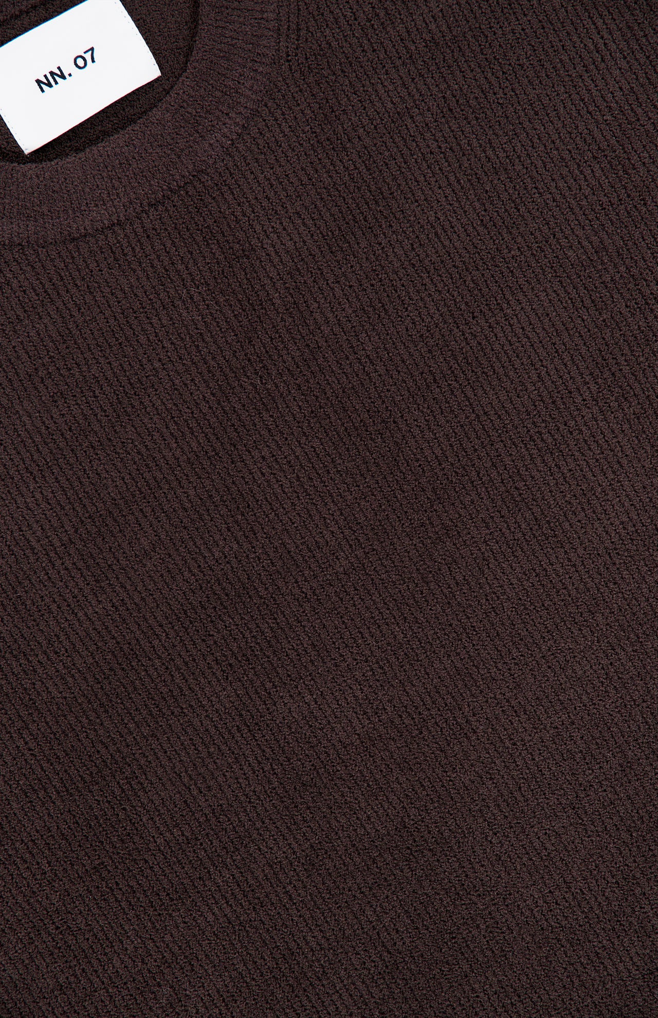 Here’s a revised version using the provided product data: Close-up of the NN07 Danny Crewneck Sweater in chocolate brown, featuring a ribbed crew neck and a white neckline tag with the brand name. Crafted from a lightweight polyester blend, this sweater offers both comfort and contemporary style in a modern silhouette.