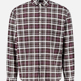 The NN07 Deon Checkered Long Sleeve Shirt is crafted from organic cotton and features a relaxed fit with long sleeves, a classic collar, and white buttons down the front. Showcasing a stylish black, white, and purple checked pattern, this shirt is displayed against a plain white background.