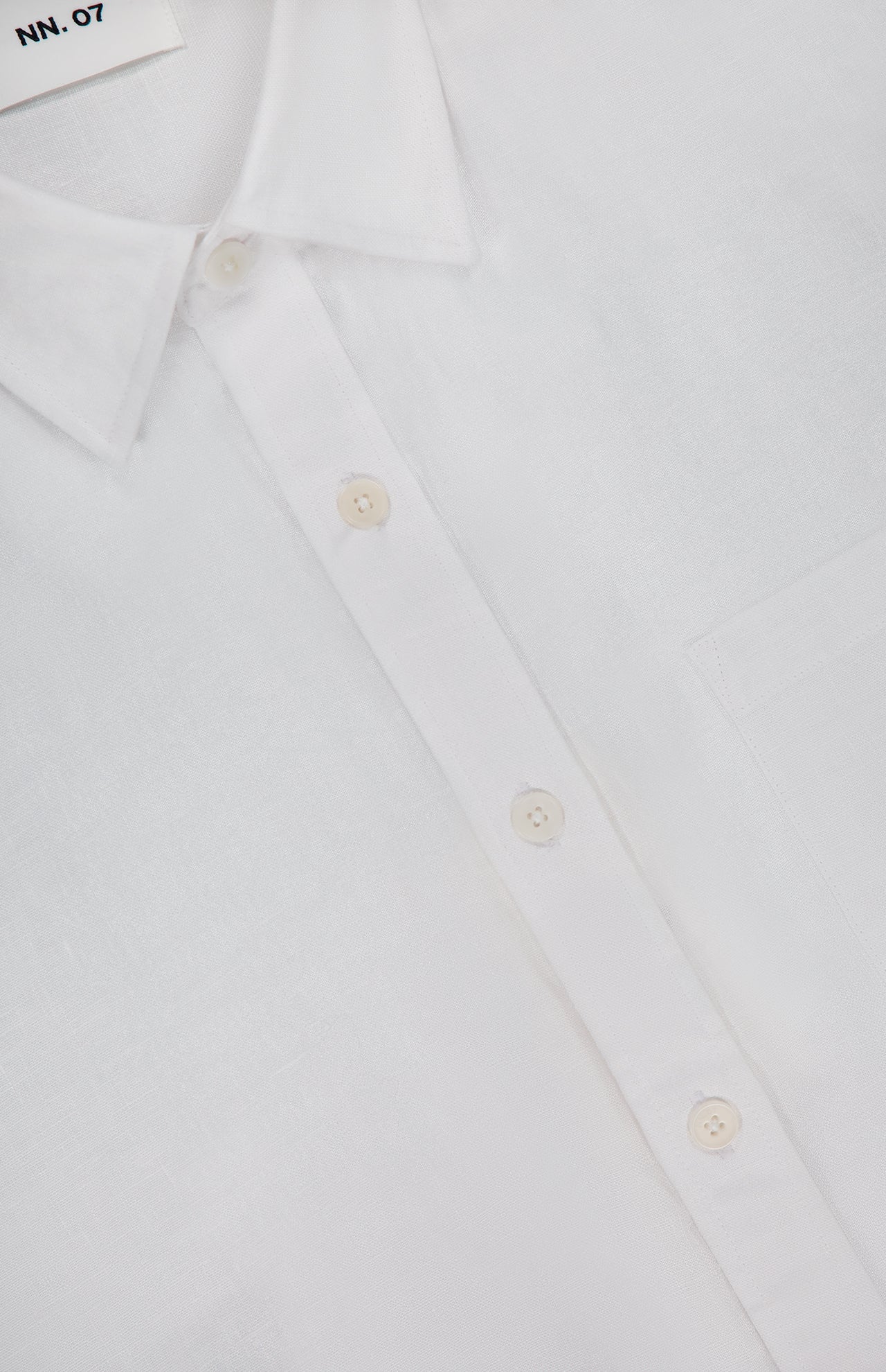 Close-up of the Deon Short Sleeve Linen Shirt by NN07, crafted from white linen with a pointed collar, white buttons, and a chest pocket—a timeless pick for modern-casual style.