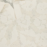 Close-up of the NN07 Ryan Flower Design Short Sleeve Shirt in ivory knit, featuring a subtle jacquard flower pattern and a white NN07 label sewn inside the collar.