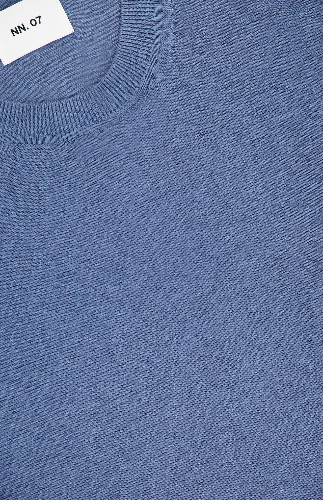 A close-up of the NN07 Ted Linen Crewneck Sweater in light blue highlights its ribbed collar and soft linen texture. A white NN07 label is partially visible near the neckline of this breathable men's pullover.