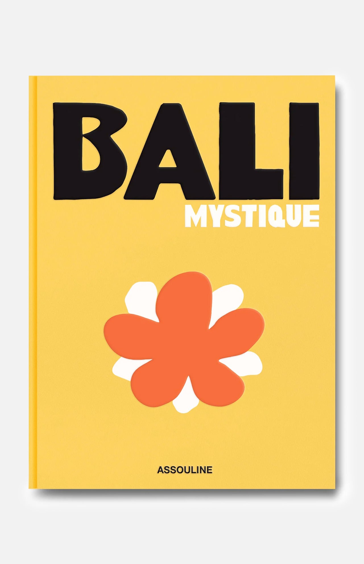 A yellow book cover titled Bali Mystique in bold black and white letters features a large, stylized orange and white flower below the title. Reflecting the spirit of Bali travel and its vibrant surfing community, this edition captures the island’s unique allure. The brand name ASSOULINE is printed at the bottom.