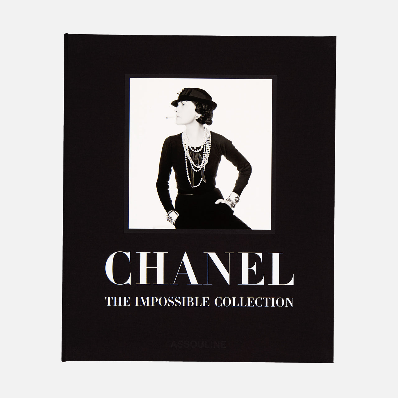 The cover of Chanel: The Impossible Collection by ASSOULINE showcases a black-and-white photo of a woman in classic Chanel style on a black background, perfectly reflecting the brand’s timeless elegance and modern luxury.