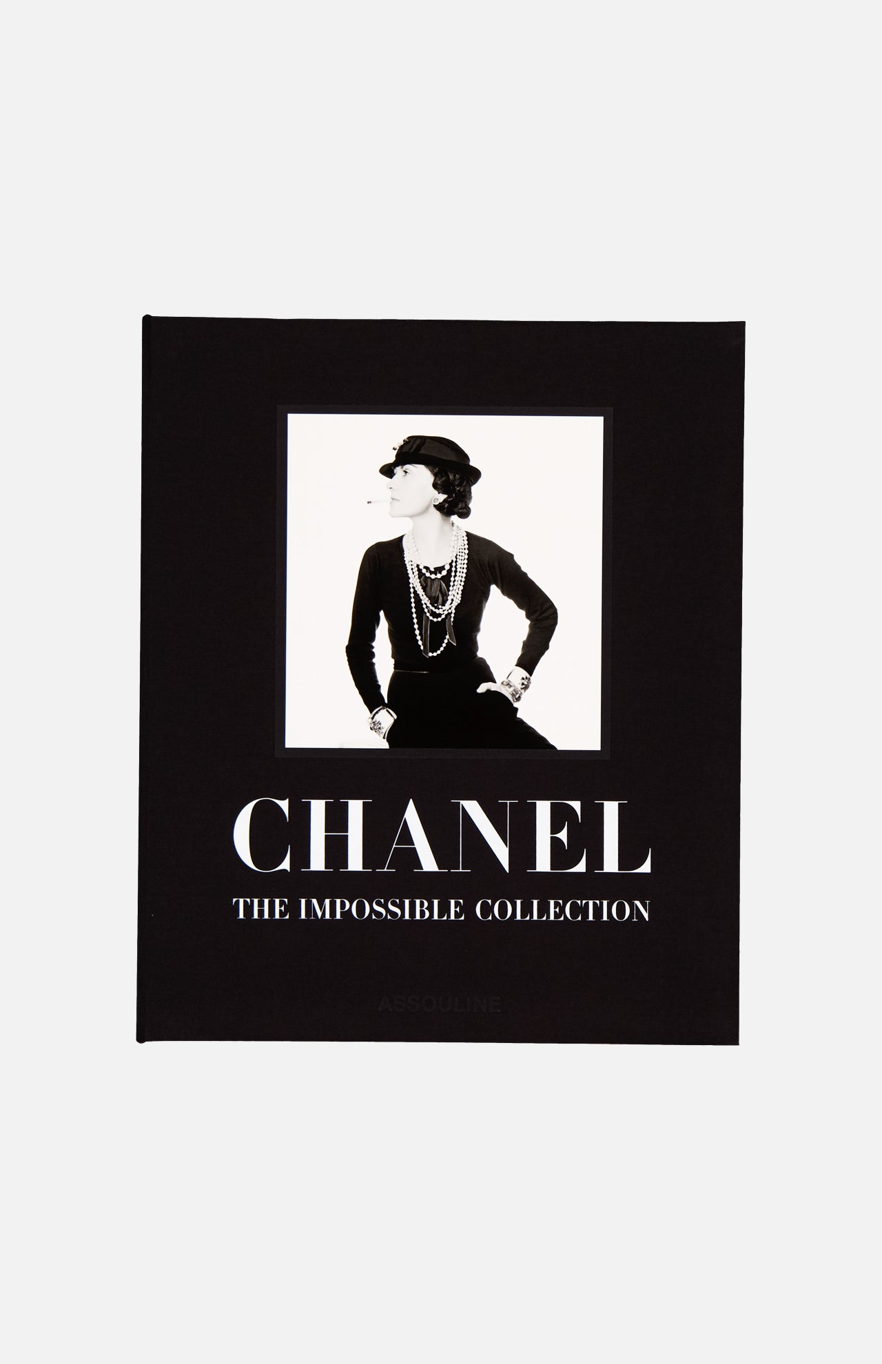 The cover of Chanel: The Impossible Collection by ASSOULINE showcases a black-and-white photo of a woman in classic Chanel style on a black background, perfectly reflecting the brand’s timeless elegance and modern luxury.