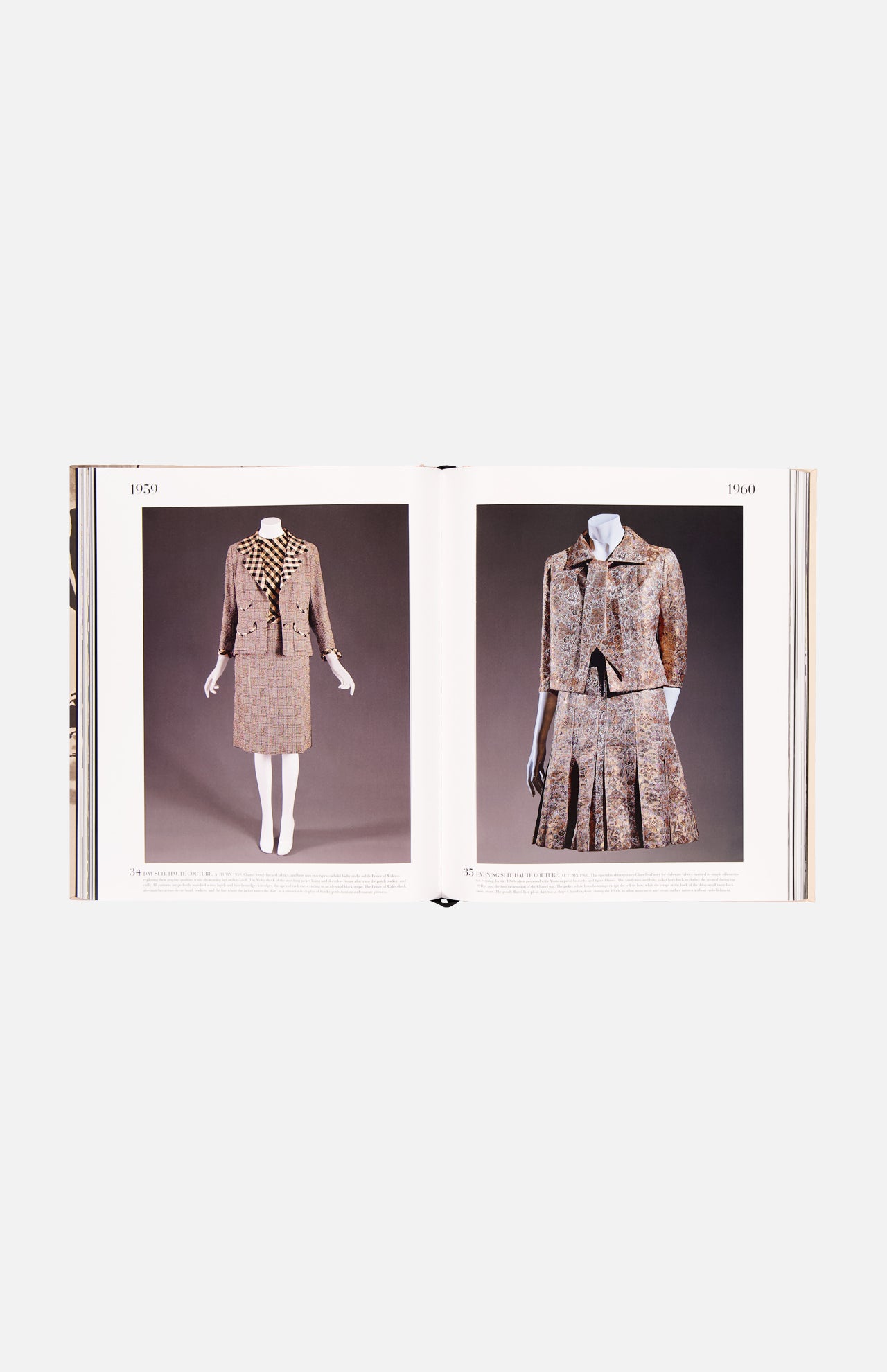 An open book from ASSOULINE’s "Chanel: The Impossible Collection" displays vintage women's suits—one a tailored skirt suit, the other a pleated skirt with matching jacket, both showcasing Chanel’s luxe minimalism in patterned fabrics.