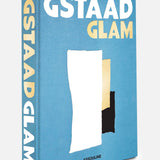 A blue hardcover book titled “Gstaad Glam” by ASSOULINE, inspired by the luxurious Swiss Alps resort and featuring abstract white, gold, and black shapes on the cover.