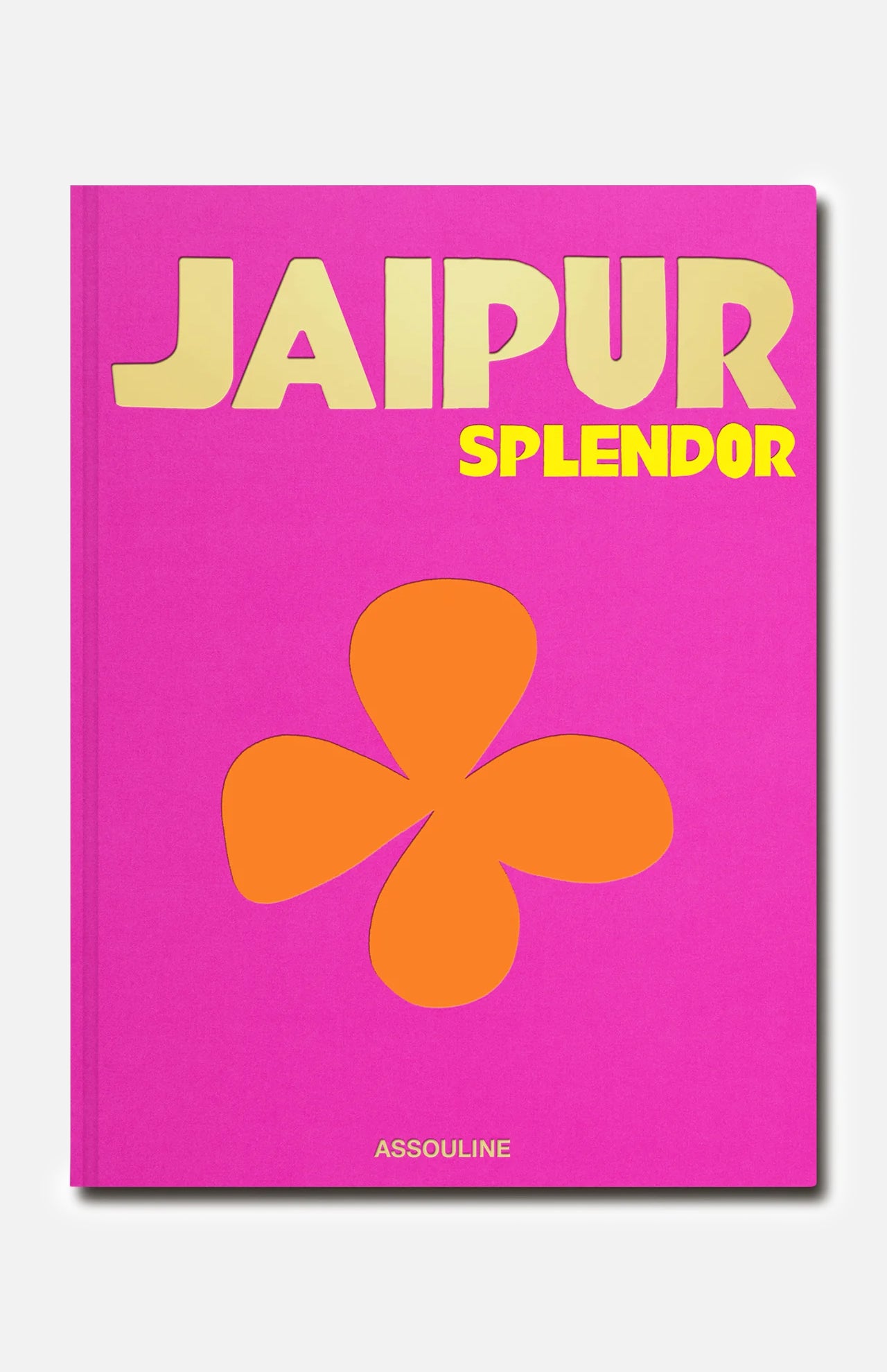 A vibrant pink book cover titled Jaipur Splendor features bold yellow text, a striking orange four-petal floral motif inspired by designs from the City Palace Jaipur at its center, and the ASSOULINE brand name printed along the bottom.
