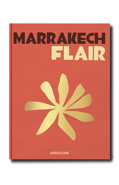 Marrakech Flair by ASSOULINE features a red cover with bold black and cream lettering, a central gold abstract floral motif inspired by the Ochre City, and the publisher's name at the bottom.
