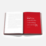 An open copy of ASSOULINE’s *Valentino Rosso* rests on a white surface, displaying one white page filled with text and one vivid red page—evocative of Rosso Valentino, the iconic shade celebrated in haute couture. The bold red page presents the quote: “Being yourself is the coolest thing you can do.”.