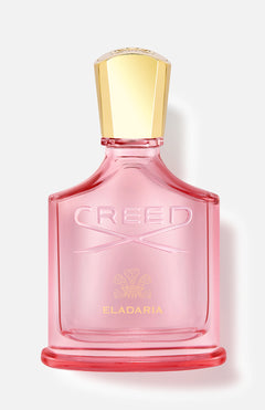 A pink glass perfume bottle with a gold cap, labeled CREED and Eladaria in gold, is displayed against a light background—an elegant presentation of Eladaria Fragrance by CREED with hints of cashmere wood.