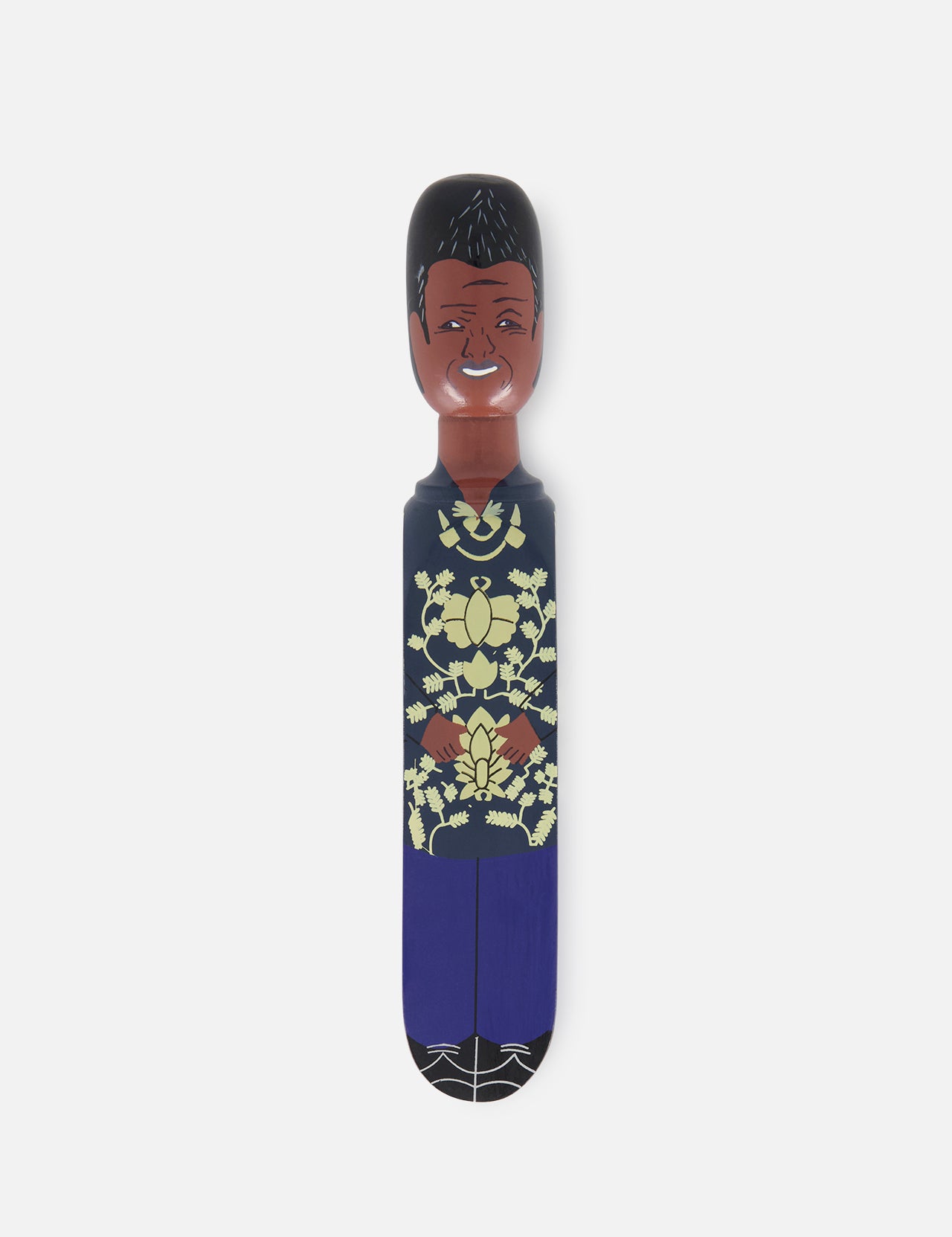 The WEDGIE 'Nels' Wood Door Stopper features a unique hand-painted design: a smiling wooden figurine with short black hair, a patterned yellow and green shirt, and blue pants standing upright against a white background.