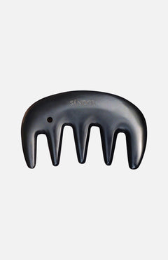 A black Gua Sha Comb by SÁNDOR, featuring four wide prongs and the brand name engraved, inspired by traditional Gua Sha techniques, is displayed against a plain white background.
