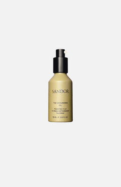 A beige bottle of SÁNDOR The Grounding Oil, a plant-based hair oil with a black pump and minimalist black text, shown against a plain white background.