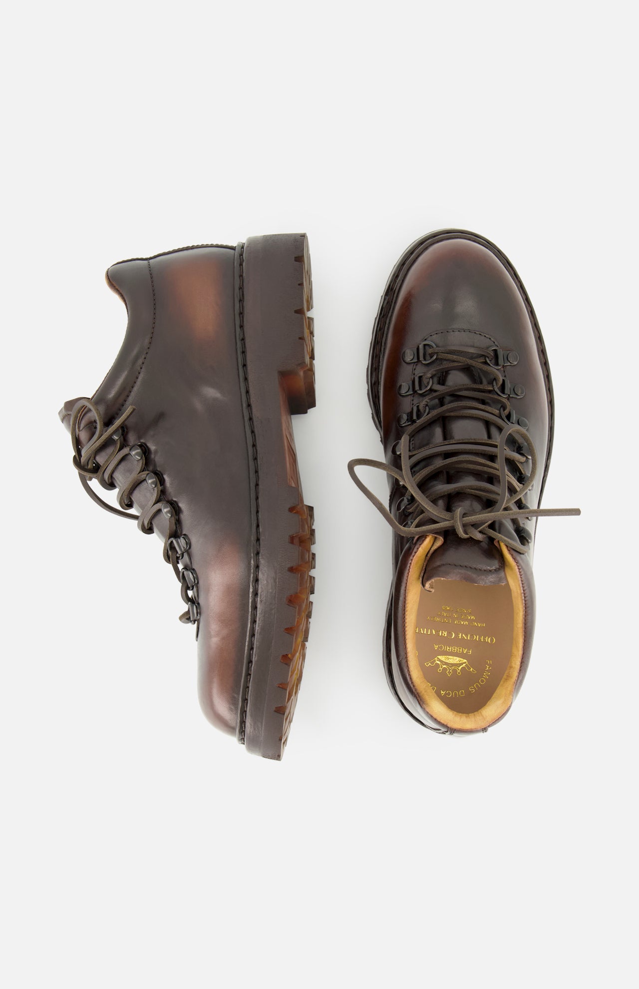 A pair of OFFICINE CREATIVE Artik Flex Lace Low Boots in dark brown Italian handcrafted leather, featuring rugged soles, metal eyelets, and black laces, displayed from the side and top on a white background.