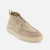 The OFFICINE CREATIVE Frame Suede Lace Chukka Boot is a tan suede boot featuring beige laces and a light rubber sole, handmade in Italy. Shown on a white background, the boot is angled to display both its side and front views.
